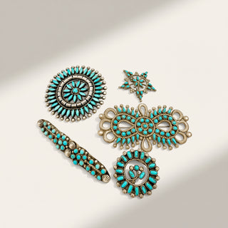 A set of five turquoise and silver jewelry components, including a large circular brooch, a matching belt buckle, a star-shaped stud, an ornate filigree charm, and a round medallion, arranged on a light beige background with soft shadows.