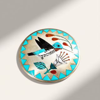 turquoise and silver brooch on a beige background