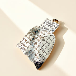 Silver stamp pendant on a beige background