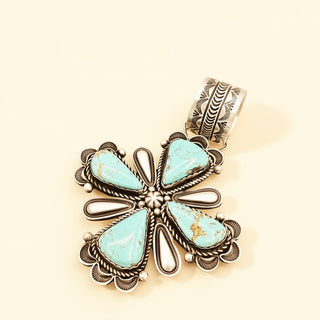 Turquoise cross pendant on a beige background
