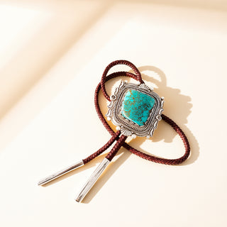 Brown rope bolo with a silver and turquoise pendant on a beige background