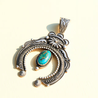 Silver pendant with turquoise stone on a beige background
