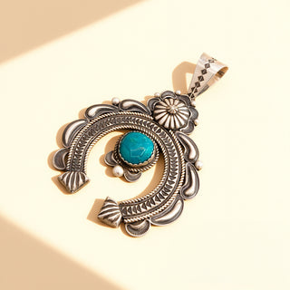 Silver pendant with a turquoise pendant on a beige background