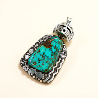 Turquoise pendant with silver design on a beige background
