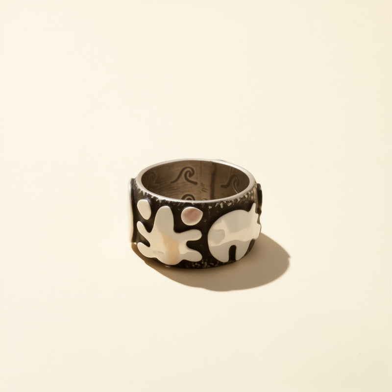 Silver ring with elephant design on a beige background