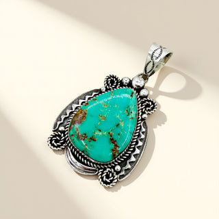 Turquoise pendant with silver decorative elements on a beige background