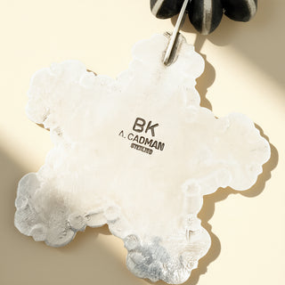 Silver star pendant with stamp on a beige background