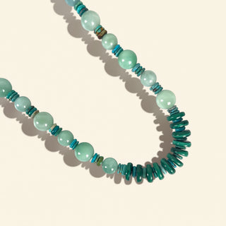 Necklace with green and blue beads on a beige background