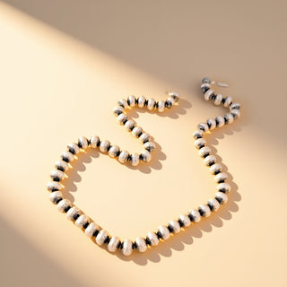 Silver beaded necklace on a beige background