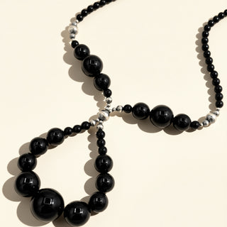 Black beaded necklace on a beige background