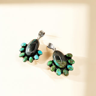 Pair of pendants with green and black stones on a beige background
