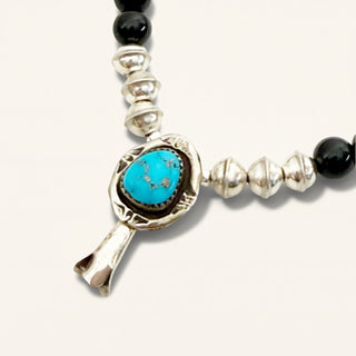Bracelet with turquoise stone and black beads on a white background