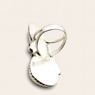 A sterling silver ring  with a curved band wrapping around the top, set against a solid light beige background.