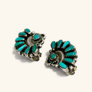 A pair of silver-toned Southwestern-style turquoise cluster earrings on a light cream background.