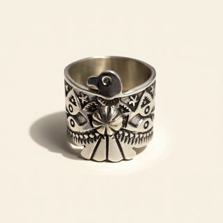 Silver ring with intricate designs on a beige background