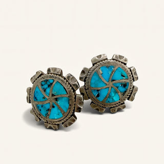 Pair of earrings with turquoise stones and metallic frames on a light background