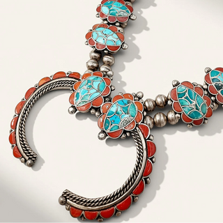A Southwestern-style silver-toned necklace featuring turquoise and coral inlay, displayed on a clean off-white background.