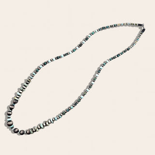 Necklace with alternating black and silver beads on a light beige background