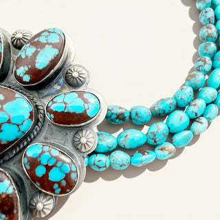 close up of turquoise beaded jewelry on a beige background