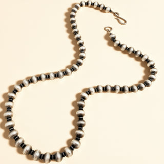 Black beaded necklace on a beige background