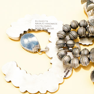 Silver necklace set on a decorative stand with 'Eli Skeets' branding.