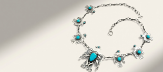 silver necklace with birds and turquoise stones on a beige background