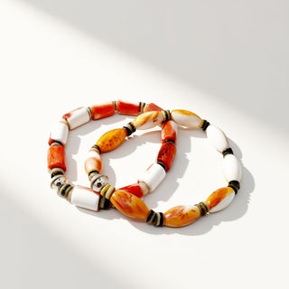 Bracelets with orange, white, and black beads on a white background