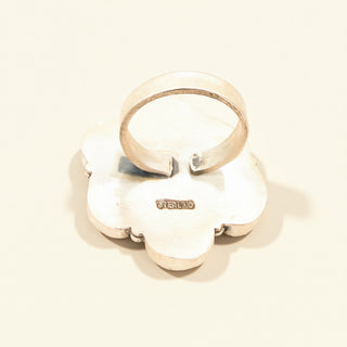 Silver ring with a textured design on a beige background