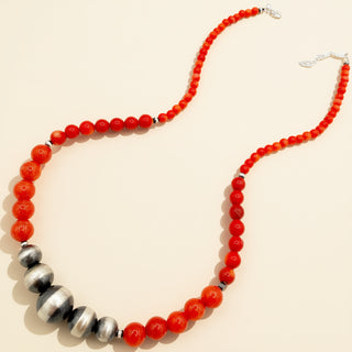 Necklace with red beads and silver accents on a beige background
