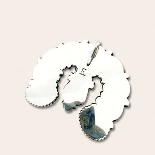 A polished sterling silver pendant with a small bail at the top, displayed on a light beige background. 