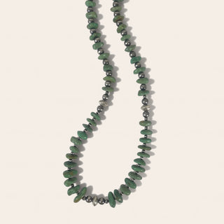 Necklace with green and black beads on a light background