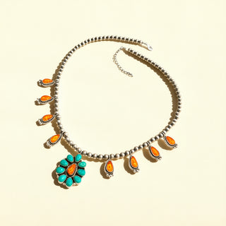 Necklace with pearls and turquoise flower pendant on a beige background