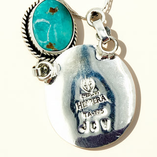 Jewelry with turquoise stone and engraved text on a white background