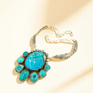 Silver necklace with turquoise centerpiece on a beige background