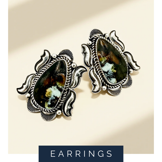 Pair of ornate earrings with gemstones on a beige background