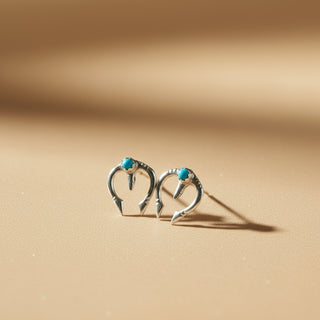 Silver earrings with turquoise stones on a textured stone surface