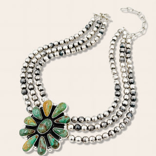 Silver beaded necklace with a green stone pendant on a white background