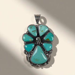 Turquoise pendant with silver setting on a beige background