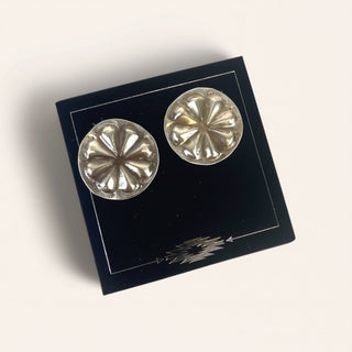 Pair of silver floral earrings on a black display card with a white background