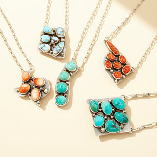Jewelry set with turquoise and orange stones on gold chains against a beige background