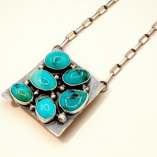 Necklace with turquoise stones and a silver chain on a beige background