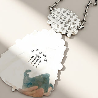 silver pendant with stamp on a beige background