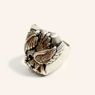 Silver ring with wing design on a beige background