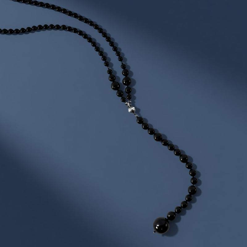 Black beaded necklace on a blue background