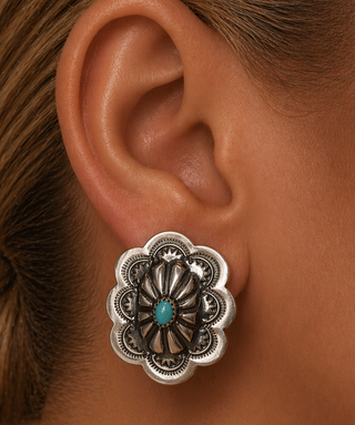 Close-up of an ear wearing a silver floral earring with a turquoise stone.