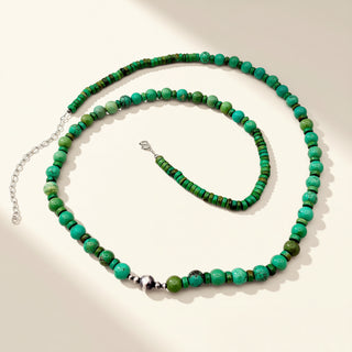 Green and black beaded necklace on a light background