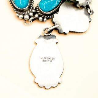 Silver pendant with 'M. SPENCER Sterling' stamp on a beige background