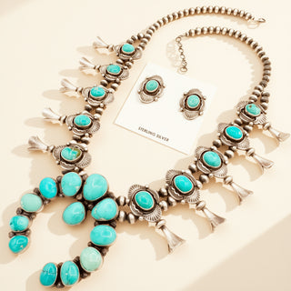 Turquoise and silver necklace with matching earrings on a light background