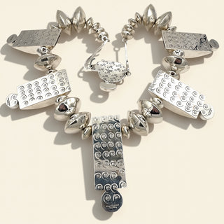 Silver necklace with various pendants on a beige background