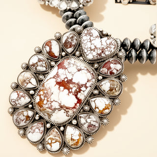 Close-up of a decorative necklace with marbled stone center on a beige background